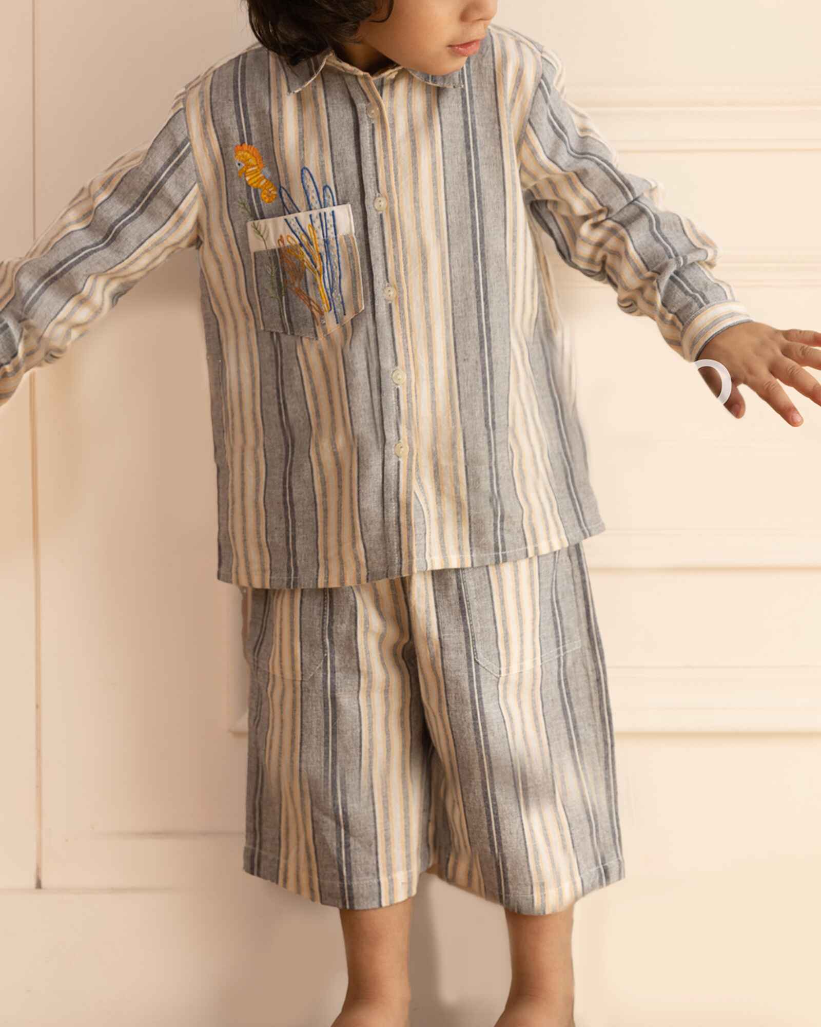 laad`s Kids' striped co-ord set with a long-sleeve shirt and shorts, featuring soft beige and gray tones. Embroidered seahorse detail adds a playful touch. Lightweight, breathable fabric for all-day comfort.