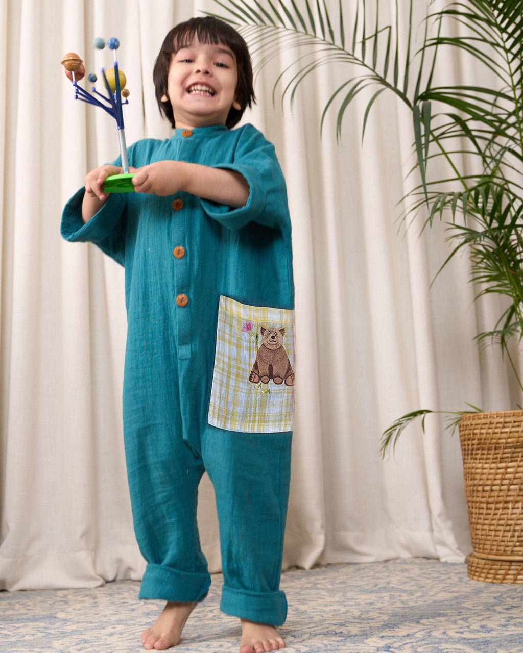 Boy wearing LAAD peacock green cotton bandhgala jumpsuit with wooden buttons and an embroidered bear patch fun large pocket.