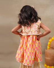 Girl wearing the Zinnia Sharara Set, featuring a vibrant checkered kurta with embroidered and printed jacket detailing along with flared and golden sharara pants, perfect for festive occasions.